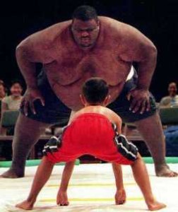 A David and Goliath situation: sumo wrestler towers over a small boy