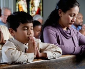 A boy and his mother pray in church