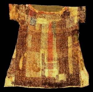 A child's garment found by archaeologists south of Cairo. It was woven from coloured wools as a single piece of cloth folded over at the shoulders, It appears to have been darned for recycling